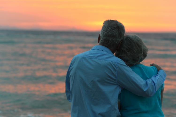 A senior couple at the beach watching the sunset
